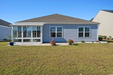 Rear view of house with a sunroom and a lawn