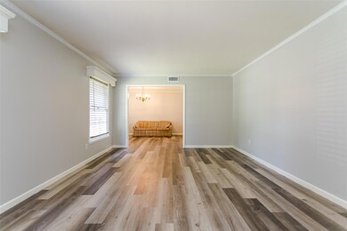 Unfurnished living room featuring wood-type flooring, an inviting chandelier, and crown molding