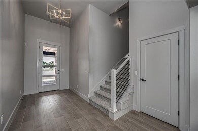 Entryway with wood finished floors, a chandelier, and stairs
