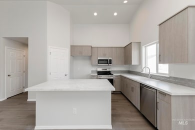 Kitchen featuring a towering ceiling, light countertops, appliances with stainless steel finishes, modern cabinets, and recessed lighting