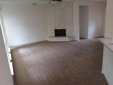 Unfurnished living room featuring a stone fireplace, carpet, and ceiling fan