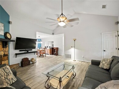 Living area featuring lofted ceiling, a ceiling fa