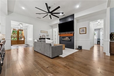 Living area featuring a glass covered fireplace, hardwood / wood-style flooring, ceiling fan, a chandelier, and recessed lighting