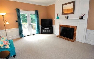 Den with masonry fireplace opens onto deck