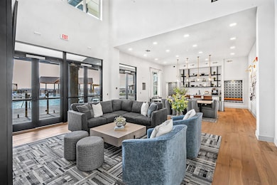 Living area featuring recessed lighting, plenty of natural light, light wood finished floors, wet bar, and a high ceiling
