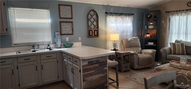 Kitchen with lofted ceiling, sink, light tile floors, kitchen peninsula, and ornamental molding