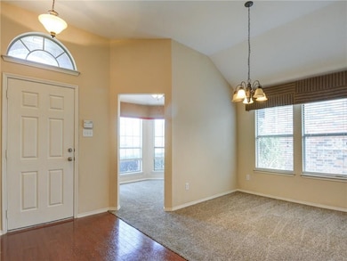 Carpeted entryway featuring lofted ceiling, wood finished floors, and a chandelier