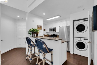 Kitchen with dark stone counters, a kitchen bar, white cabinets, a peninsula, and dark wood-type flooring