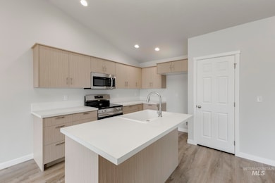 Kitchen with light brown cabinetry, appliances with stainless steel finishes, modern cabinets, light countertops, and light wood-style flooring
