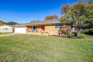 Ranch-style home with brick siding, driveway, covered porch, roof with shingles, and an attached garage