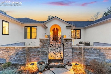 Exterior entry at dusk with fence, a gate, stucco siding, and stone siding