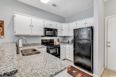 Kitchen featuring black appliances, white cabinets