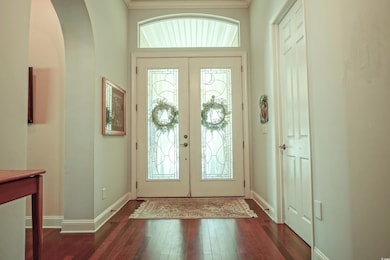 Foyer entrance featuring arched walkways, wood-type flooring, french doors, and crown molding