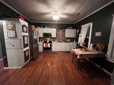 Kitchen with crown molding, white cabinetry, stainless steel appliances, and dark hardwood / wood-style floors