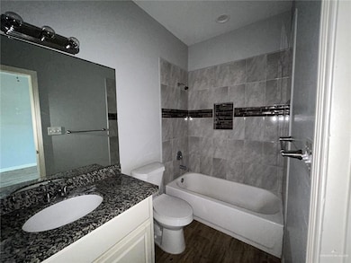 Bathroom featuring shower / bathtub combination, dark wood-style flooring, and vanity
