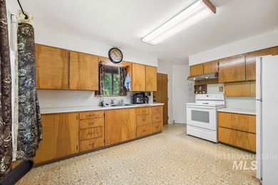 Kitchen with white appliances, light countertops, backsplash, light flooring, and under cabinet range hood