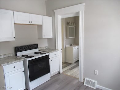 Kitchen with white cabinetry, light wood-type flooring, and white electric stove