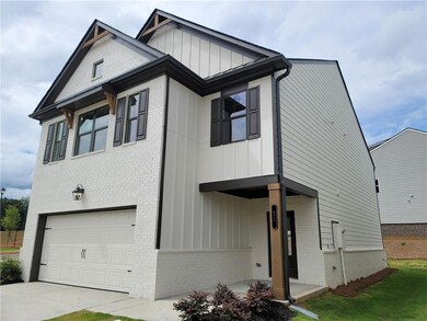 View of front facade with brick siding, a garage, board and batten siding, and driveway