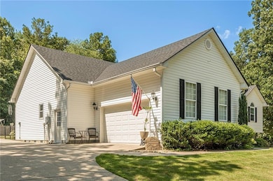 View of front facade with driveway, a garage, and roof with shingles