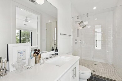 Bathroom featuring tile flooring, ceiling fan, oversized vanity, walk in shower, and toilet