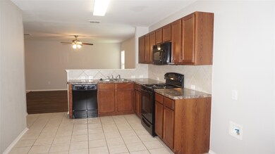 Kitchen with tasteful backsplash, black appliances, brown cabinets, light tile patterned floors, and a peninsula