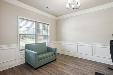 Sitting room with crown molding, a chandelier, dark wood-style flooring, a wainscoted wall, and a decorative wall