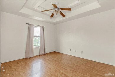 Unfurnished room with ceiling fan, baseboards, light wood-style floors, and a raised ceiling