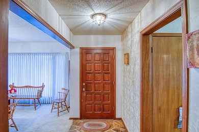 Entrance foyer with a textured ceiling and a textured wall
