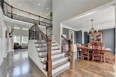 Stairs featuring a high ceiling, a chandelier, wood finished floors, crown molding, and recessed lighting