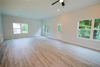 Spare room featuring crown molding, a ceiling fan, baseboards, wood finished floors, and recessed lighting
