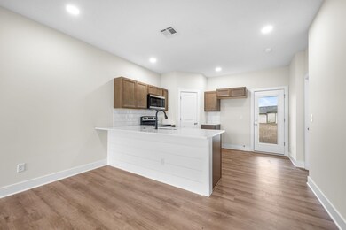 Kitchen featuring decorative backsplash, a peninsula, recessed lighting, light wood-type flooring, and brown cabinetry