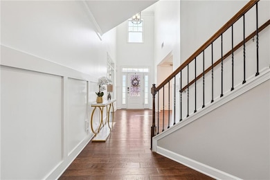 Foyer featuring stairway, crown molding, an inviting chandelier, a towering ceiling, and dark wood-type flooring