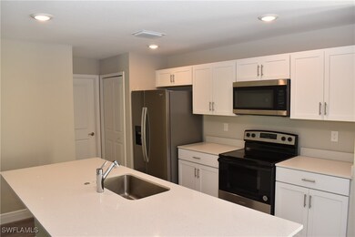 Kitchen featuring appliances with stainless steel finishes, light countertops, white cabinets, and a sink