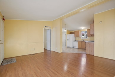 Unfurnished living room with vaulted ceiling, light wood finished floors, and ornamental molding