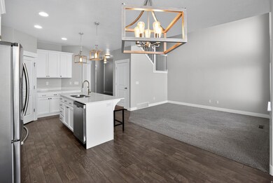 Kitchen with appliances with stainless steel finishes, a center island with sink, a kitchen breakfast bar, decorative light fixtures, and white cabinetry