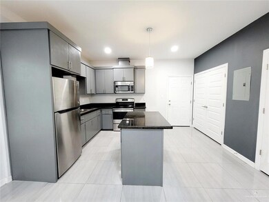 Kitchen with baseboards, electric panel, a kitchen island, stainless steel appliances, and gray cabinets