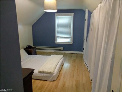 Bedroom with lofted ceiling, a baseboard heating unit, and light hardwood / wood-style floors