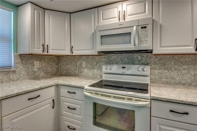 Kitchen with white appliances, white cabinetry, li