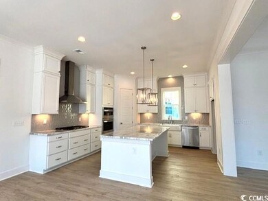Kitchen with white cabinetry, wall chimney exhaust