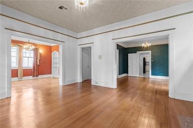 Living room opening to study/bedroom on left with French Doors (opened for photo)and formal dining room (green wall papered room)