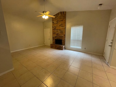 Unfurnished living room with a brick fireplace, light tile patterned floors, ceiling fan, and high vaulted ceiling