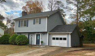 Colonial house featuring an attached garage, a chimney, and concrete driveway