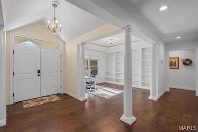 Foyer entrance featuring a chandelier, dark wood-style floors, decorative columns, lofted ceiling, and recessed lighting