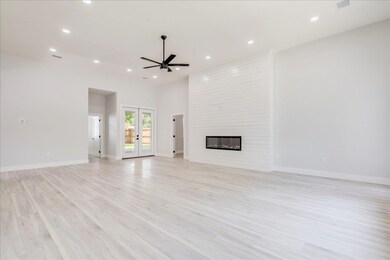 Unfurnished living room featuring ceiling fan, li