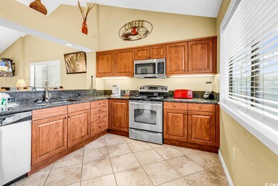 Kitchen with stainless steel appliances, a sink, brown cabinetry, and high vaulted ceiling