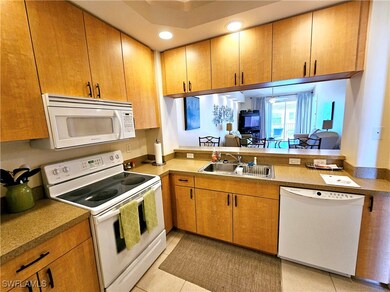 Kitchen with white appliances, light tile patterne