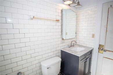 Bathroom with tile walls, toilet, and vanity