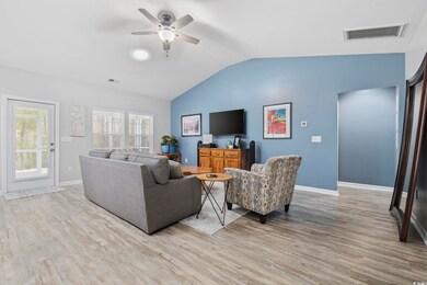 Living room with vaulted ceiling, ceiling fan, and