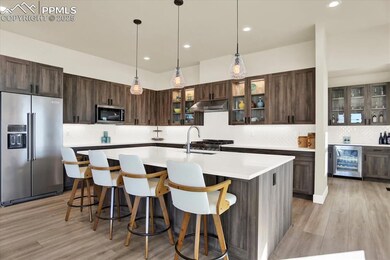 Kitchen featuring stainless steel appliances, wine cooler, under cabinet range hood, tasteful backsplash, and recessed lighting
