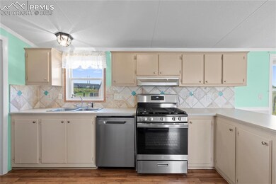Kitchen with stainless steel appliances, crown molding, light countertops, cream cabinetry, and tasteful backsplash